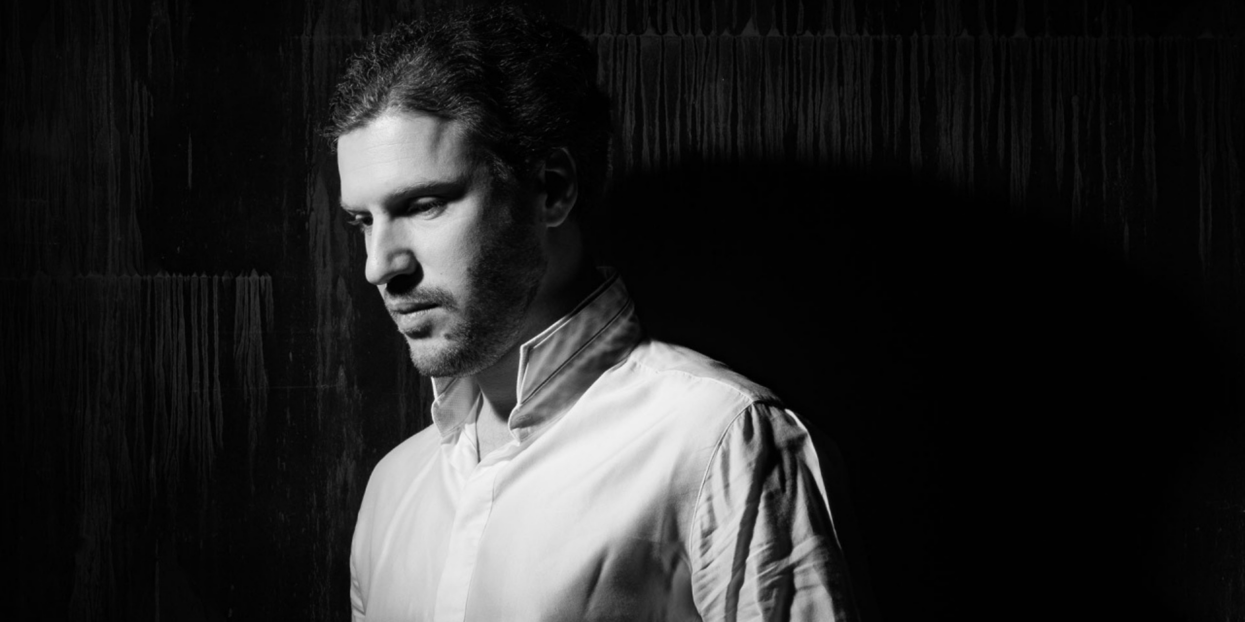 Mand i hvid skjorte foran sort baggrund.