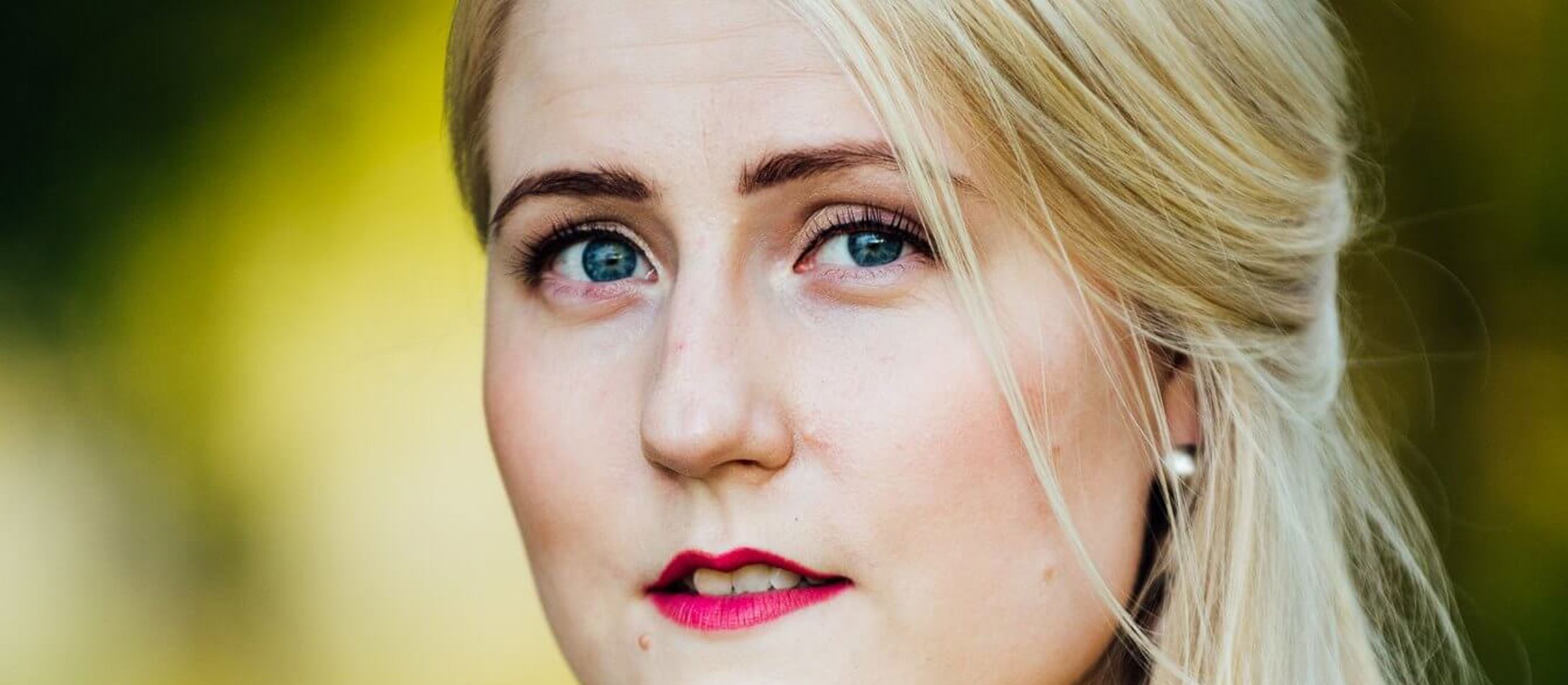 Lyshårede Johanna Nylund med rosafarvede læber og intense smukke øjne foran sløret gullig baggrund