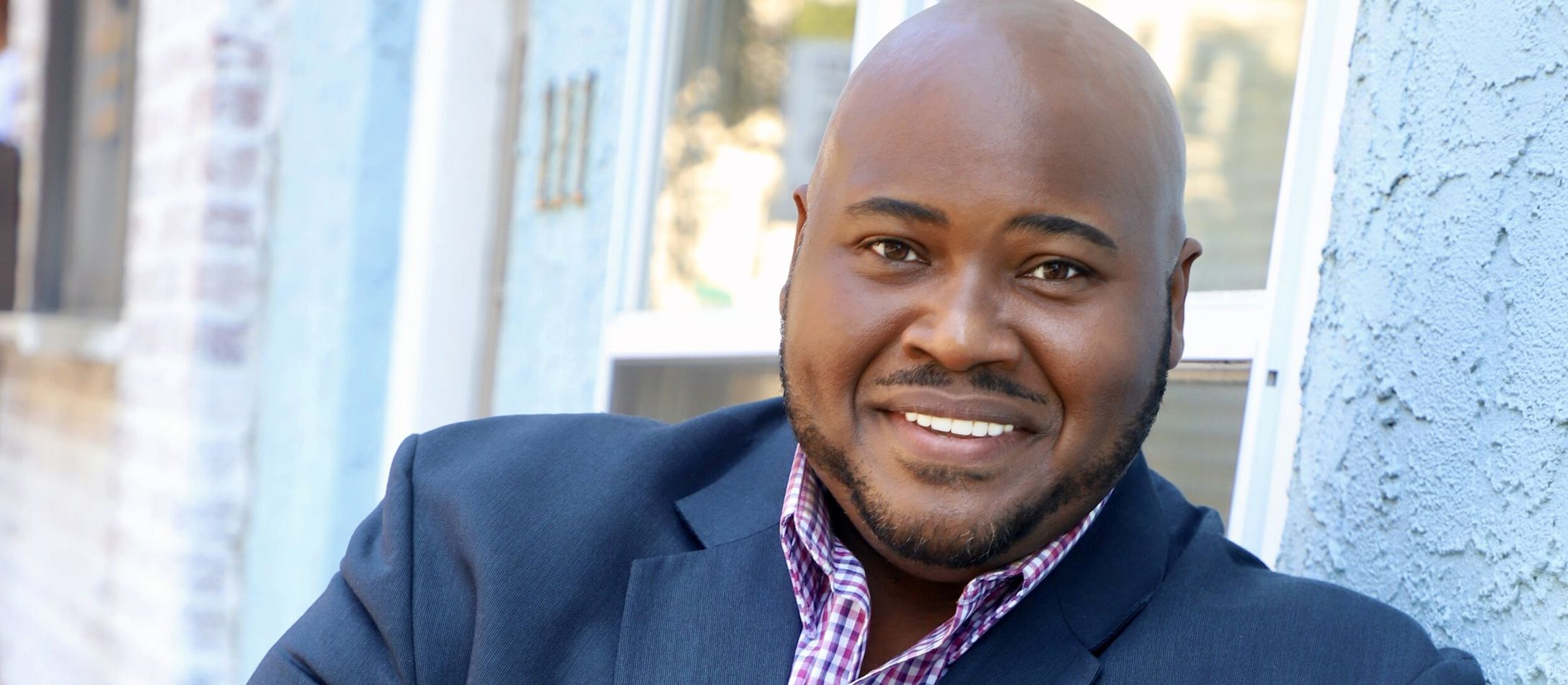 Issachah Savage smiler stort iført blå jakkesæt