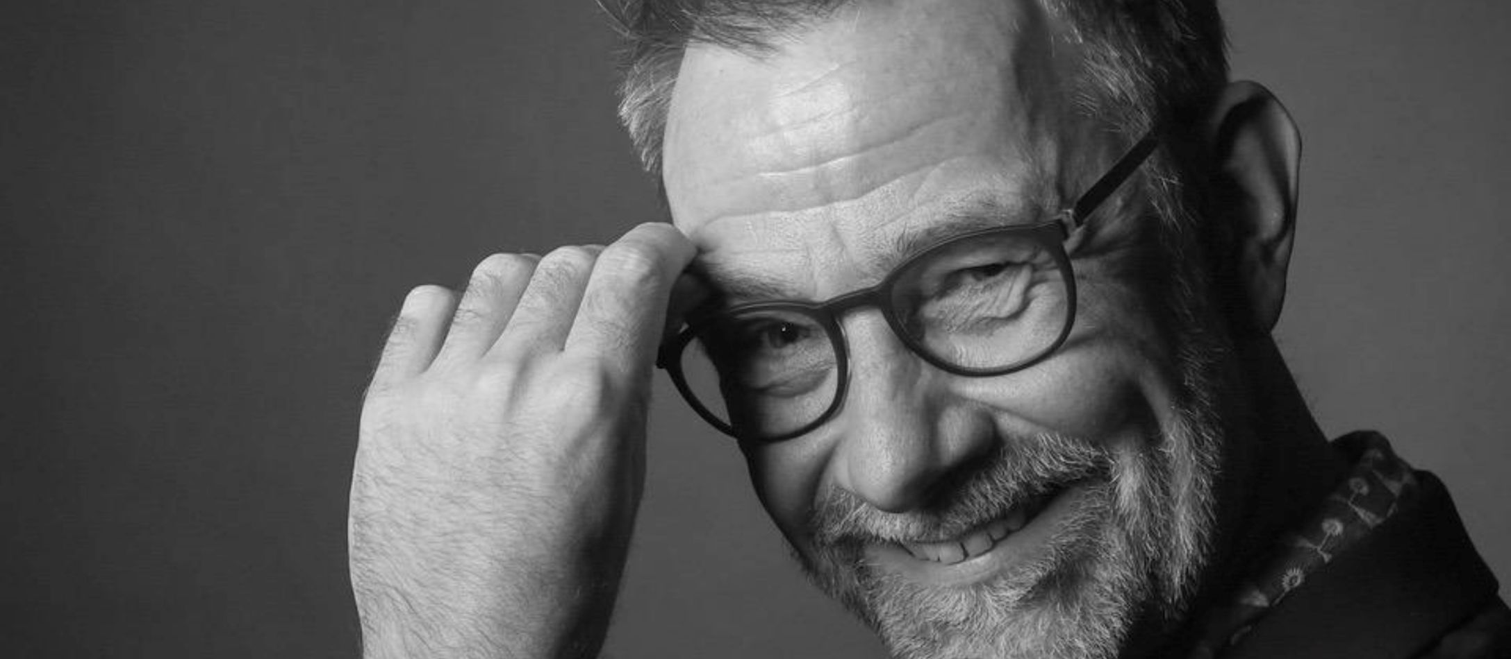 Mand med briller, kigger ind i kameraet foran en grå baggrund.