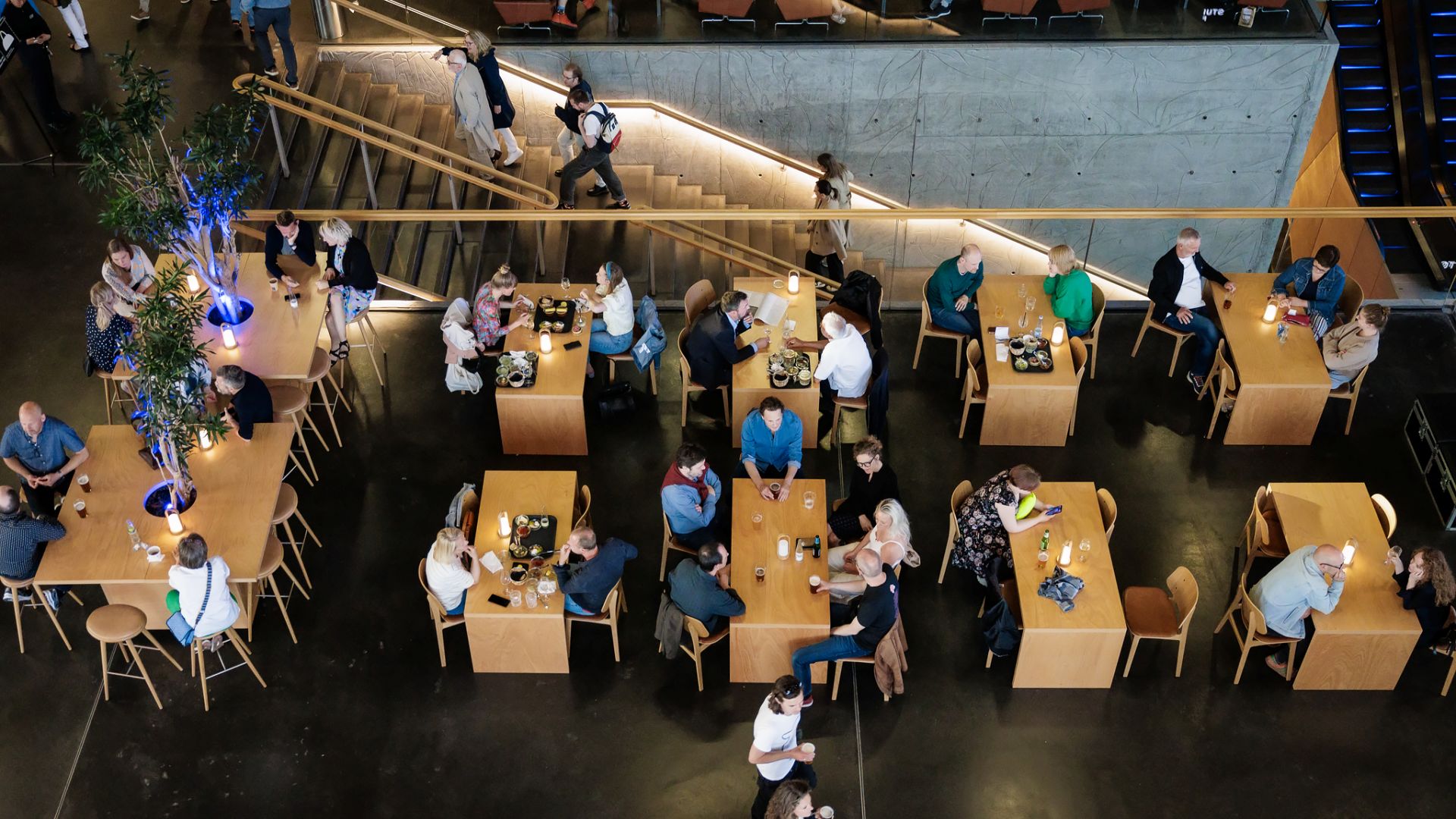 Mennesker nyder et glas i DR Koncerthusets foyer inden koncert set ovenfra.