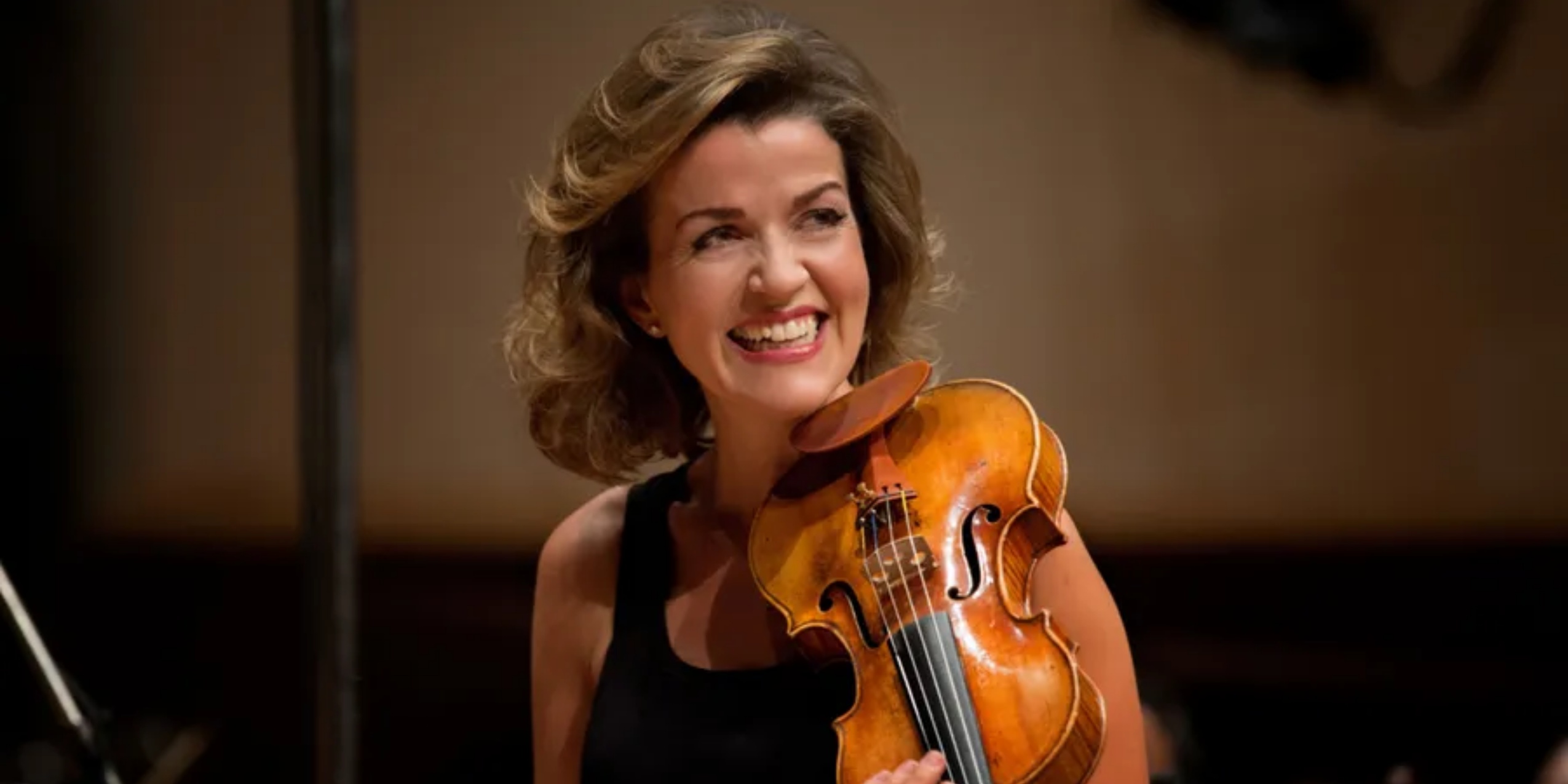 Kvinde i sort kjole, spiller smilende sin violin.