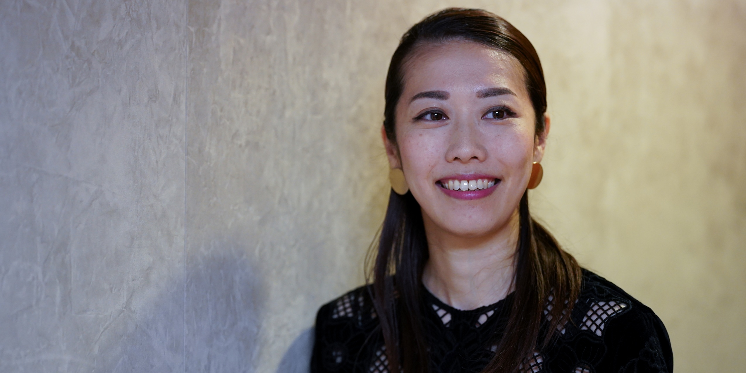 Kvinde i sort smiler foran betonvæg