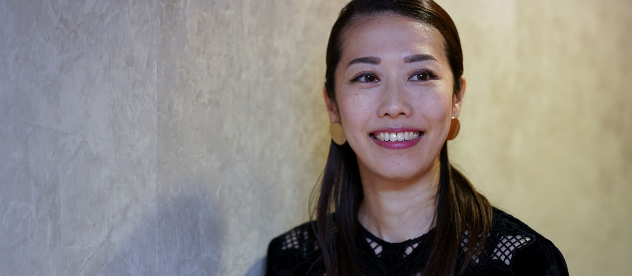 Kvinde i sort smiler foran betonvæg