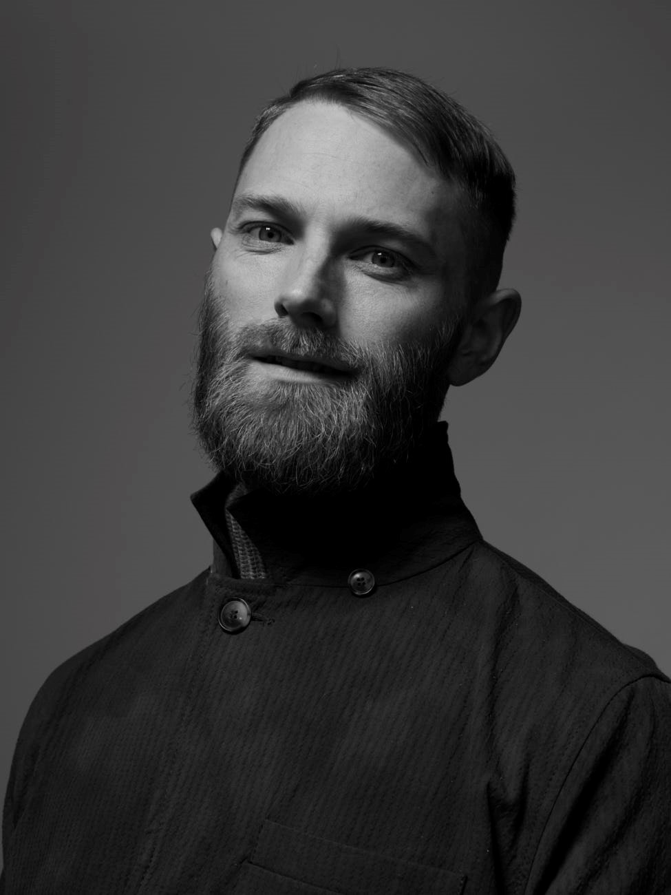 Silas Bjerregaard i sort/hvid smiler mildt med sine intense bløde øjne og unik sort skjortejakke