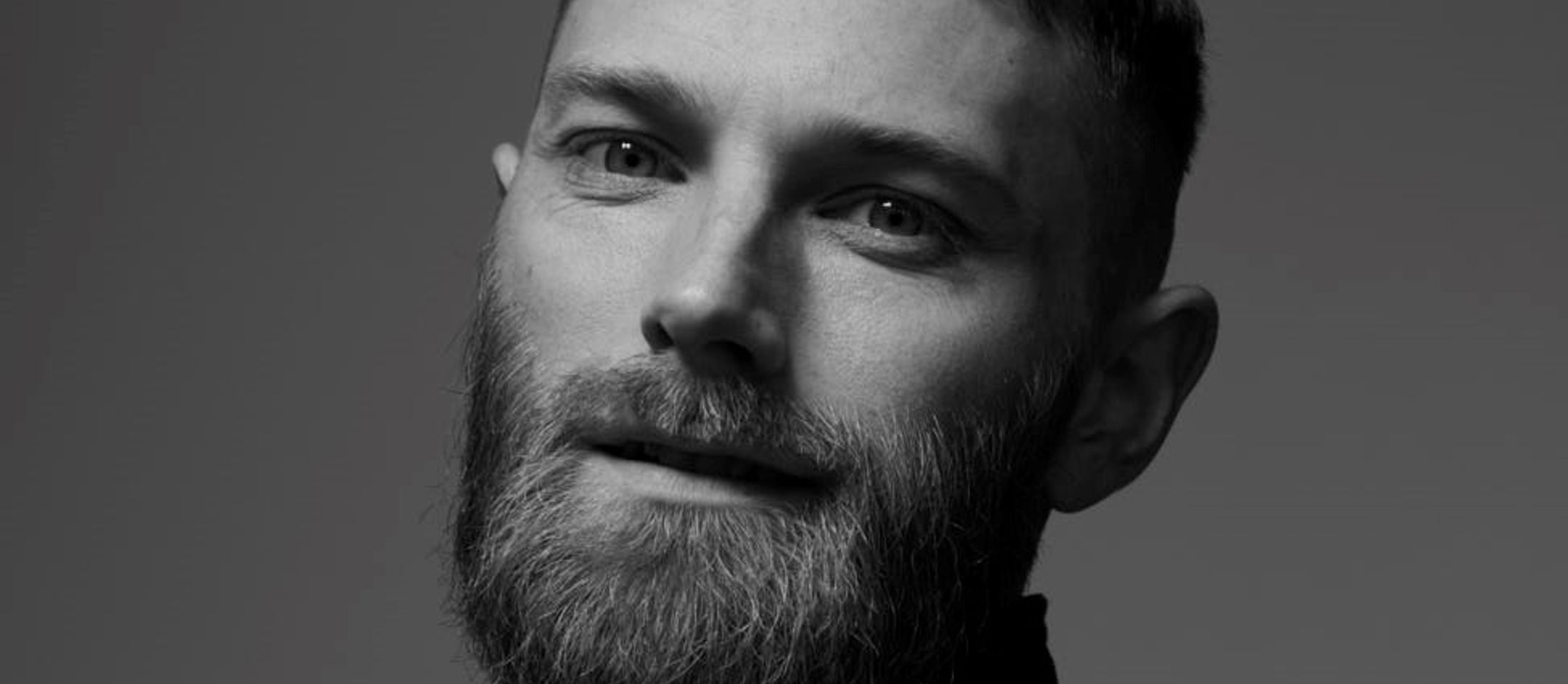 Silas Bjerregaard i sort/hvid smiler mildt med sine intense bløde øjne og unik sort skjortejakke