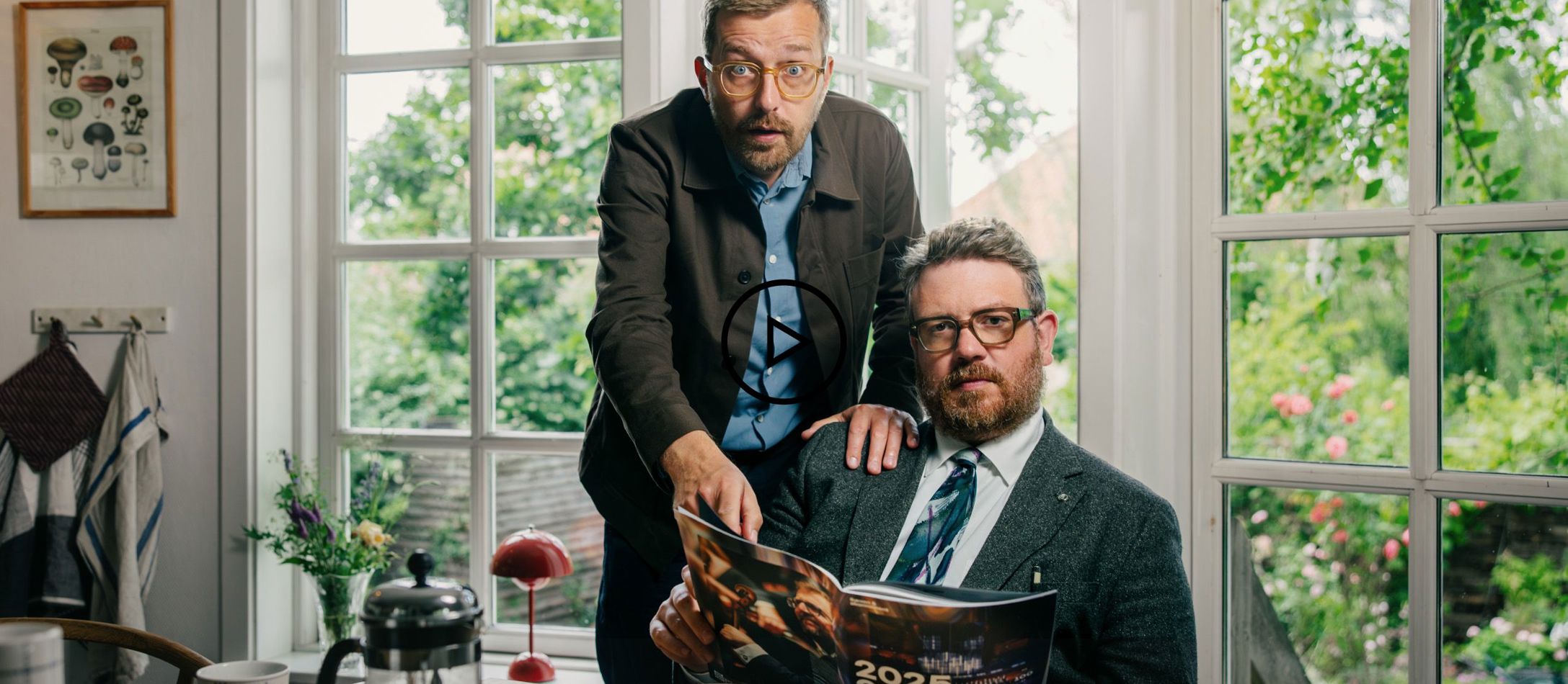 Video logo - Rasmus Bruun og Frederik Cilius sidder i et køkken og ser overrasket ud