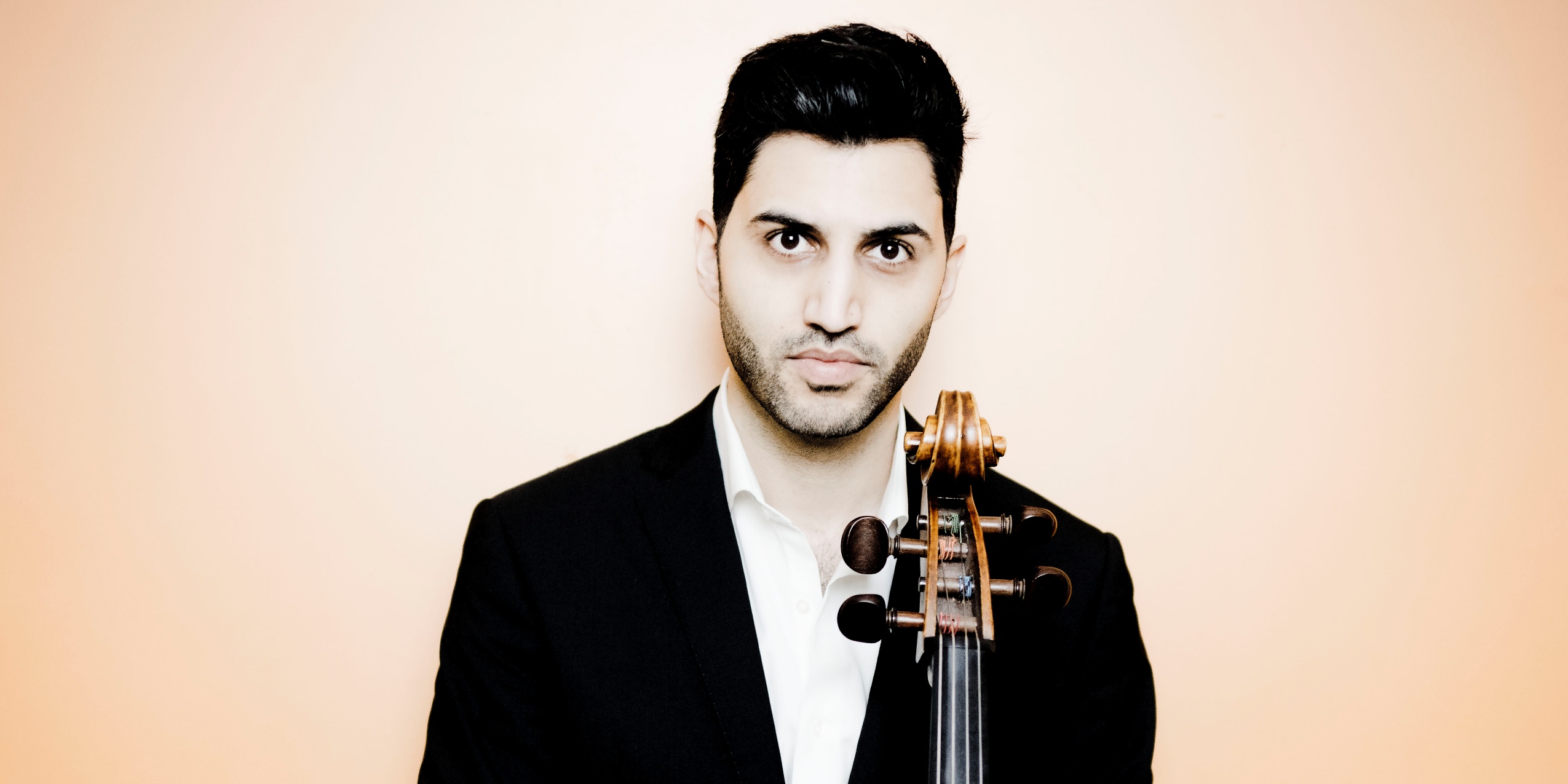 Mand med sort blazer, står med sin cello og kigger ind i kameraet.