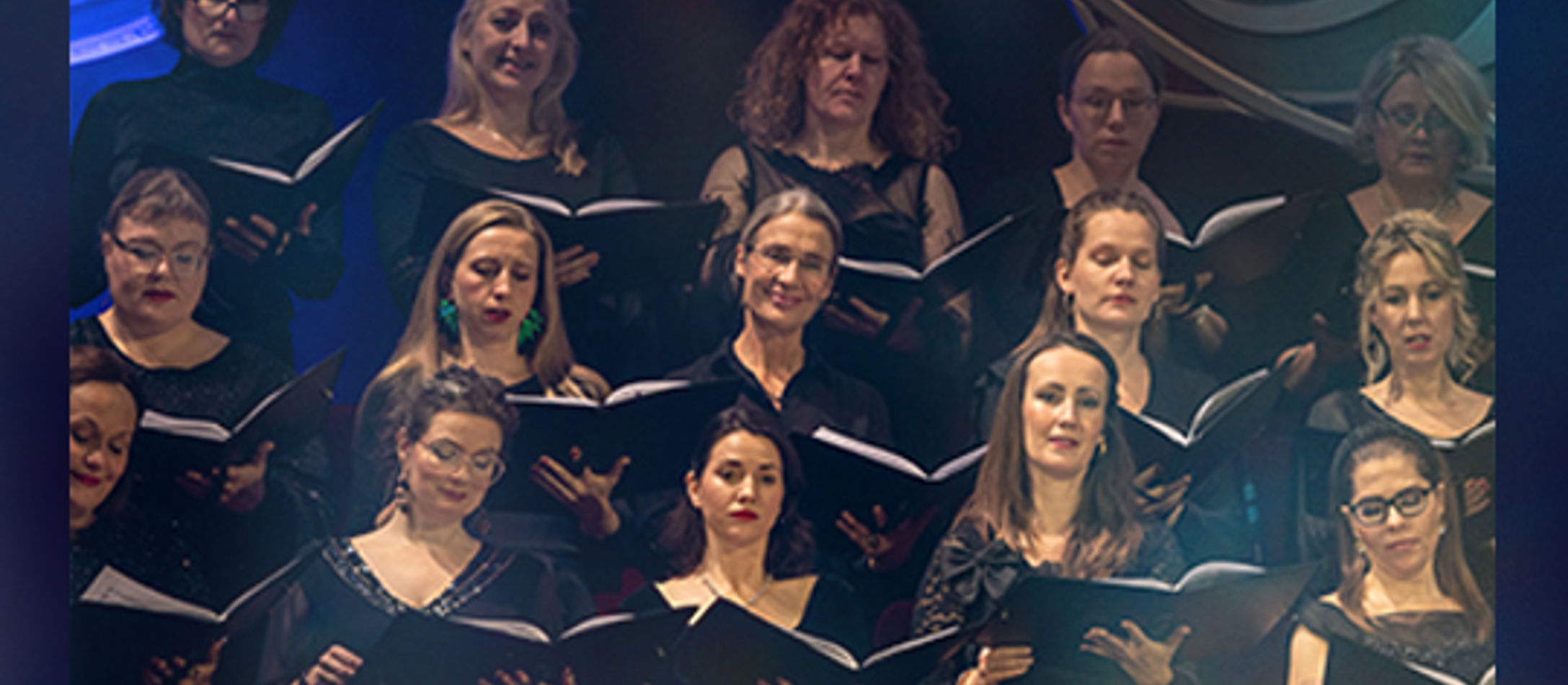 Et modent kort med femten kvinder koncentreret med sanghæfter i hænderne til Gaming X Symphony-koncerten i koncertsalen.
