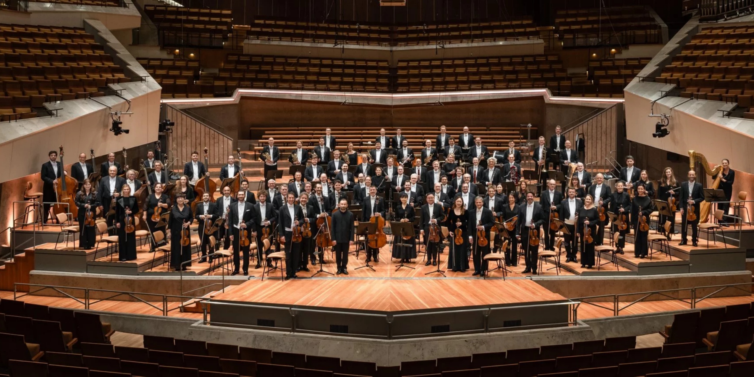 Orkester stående på en scene i en koncertsal