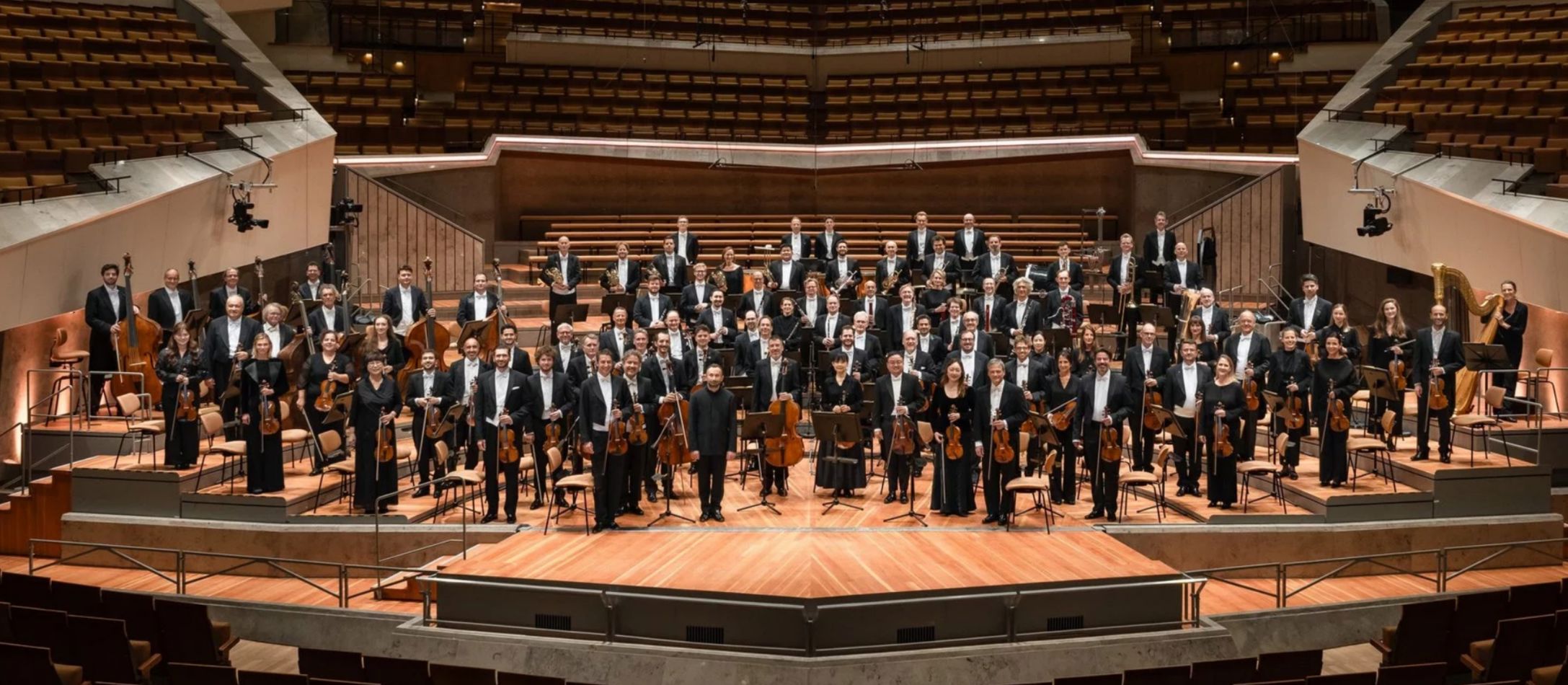 Orkester stående på en scene i en koncertsal
