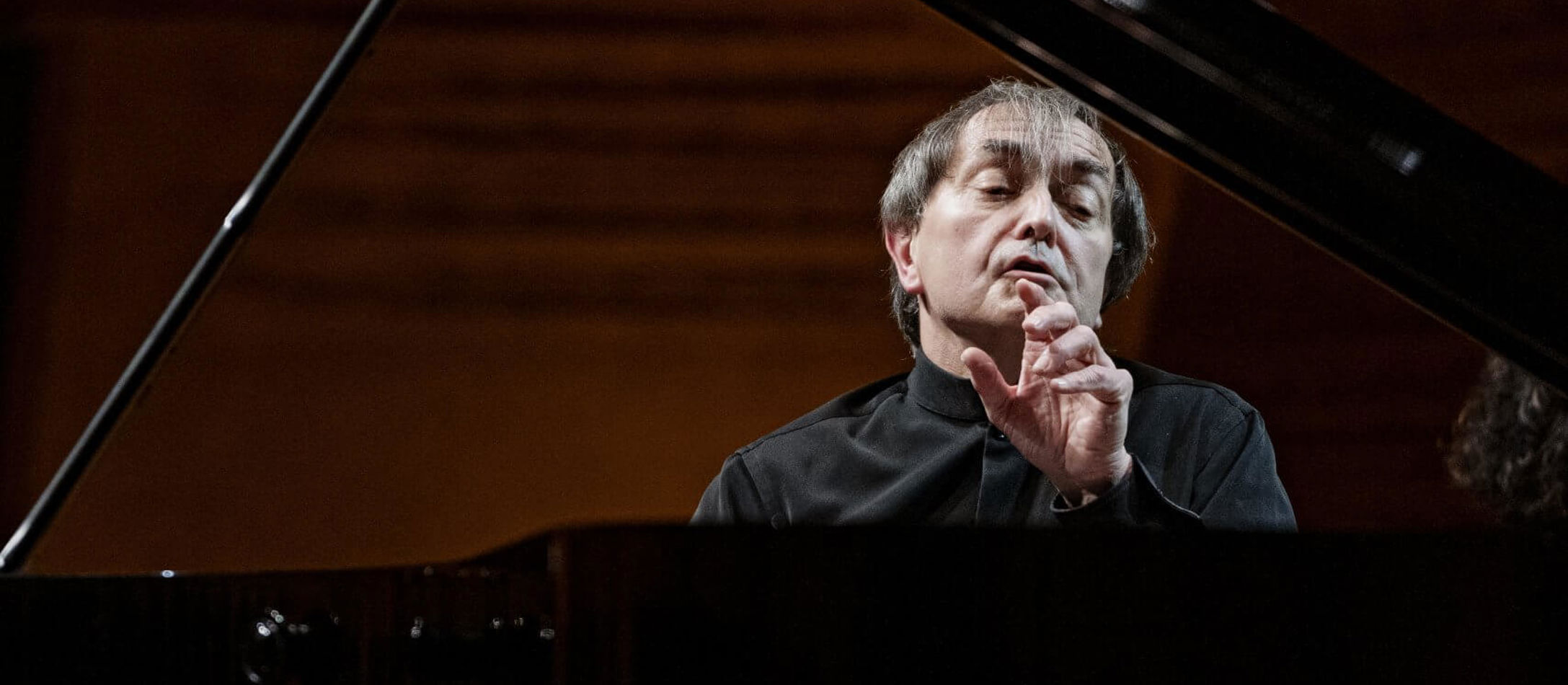 Alvorlige Pierre Laurent Aimard foran reflekterende klaver under koncert