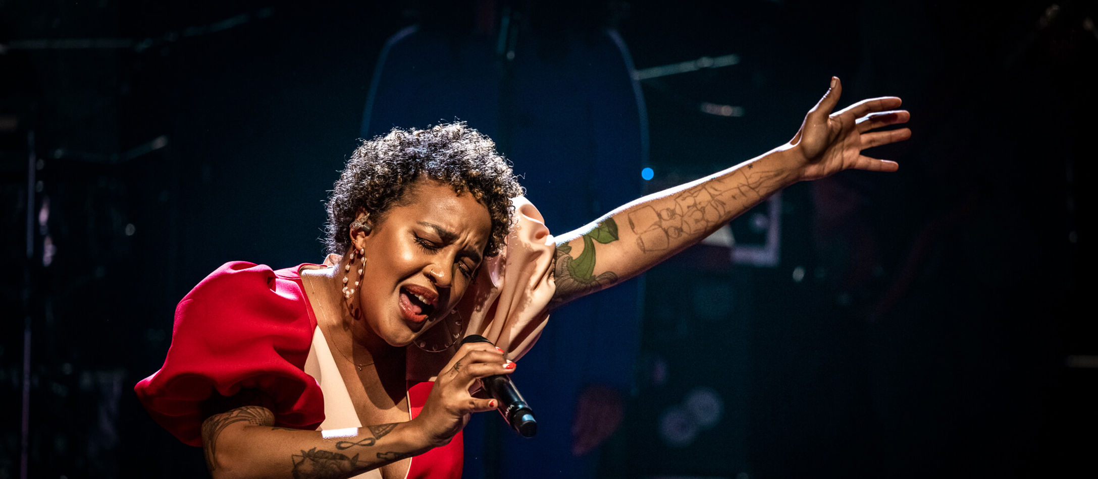 Afroamerikanske afstamning Barbara Moleko iført rød elegant kjole synger dybfølt med lukkede øjne