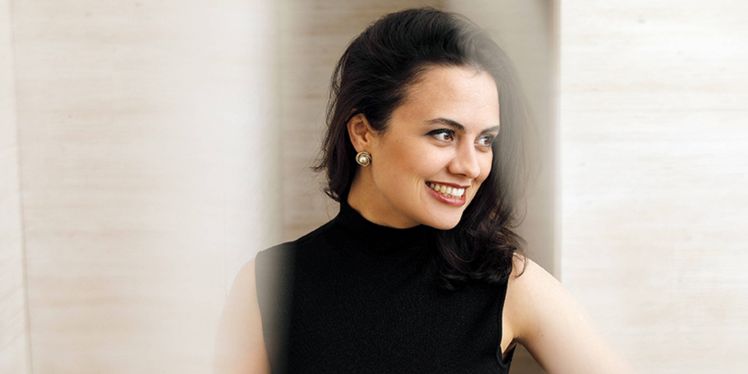 Kvinde i sort kigger til siden smilende.