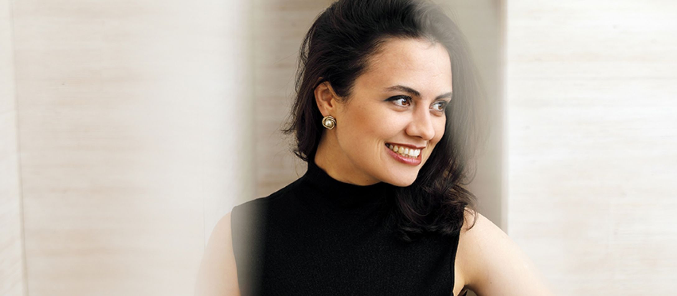 Kvinde i sort kigger til siden smilende.