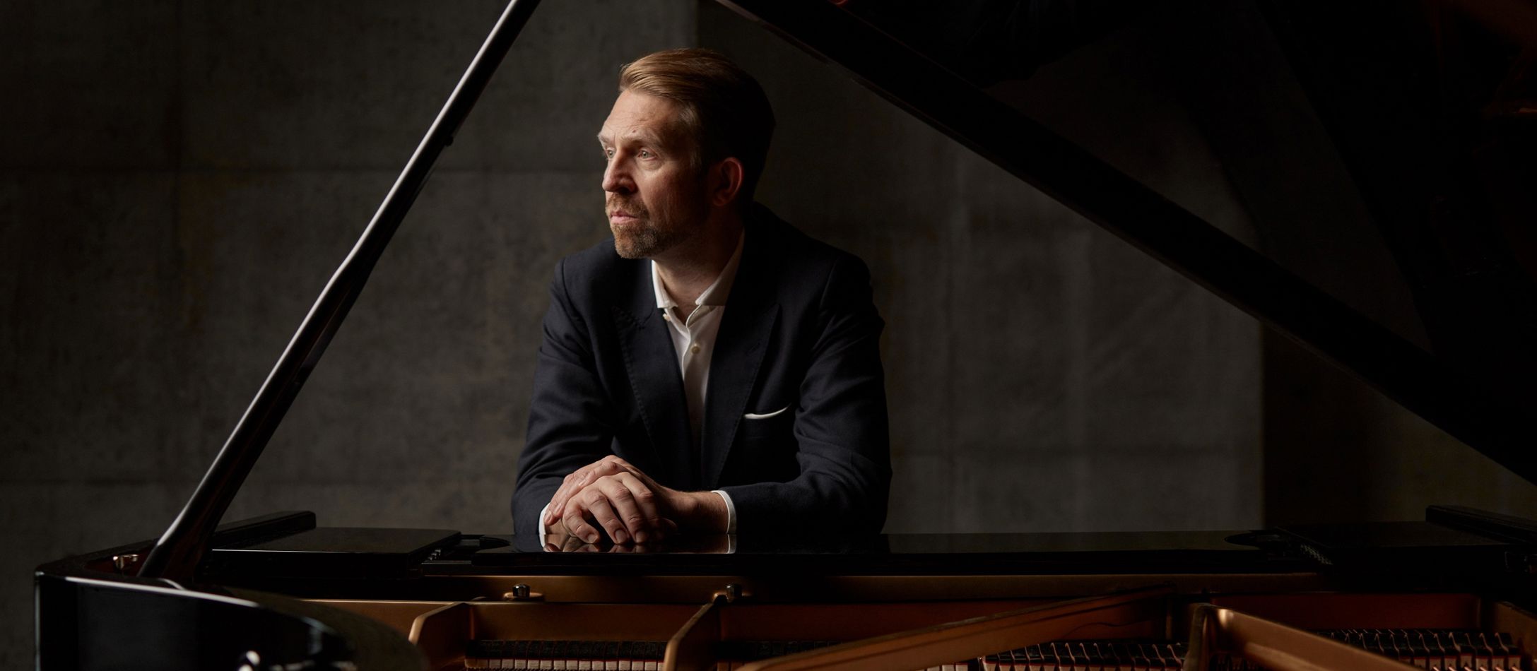 Mand hvilende op ad et åbent klaver foran grå beton væg.