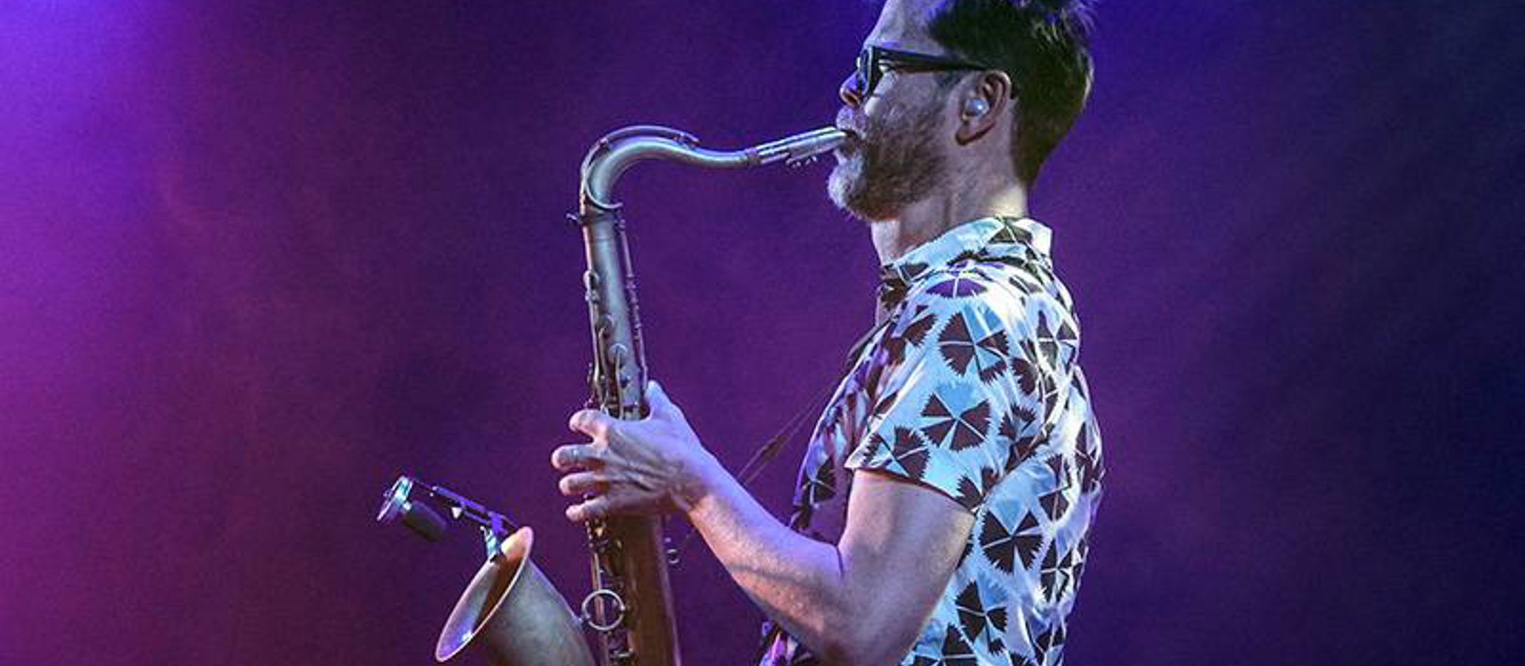 Donny McCaslin spiller saxophon foran blålilla baggrund