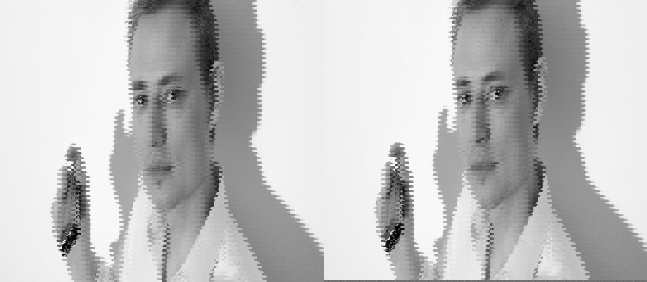 Mathias Heise med harmonika i højre hånd iført hvid skjorte foran hvid baggrund.