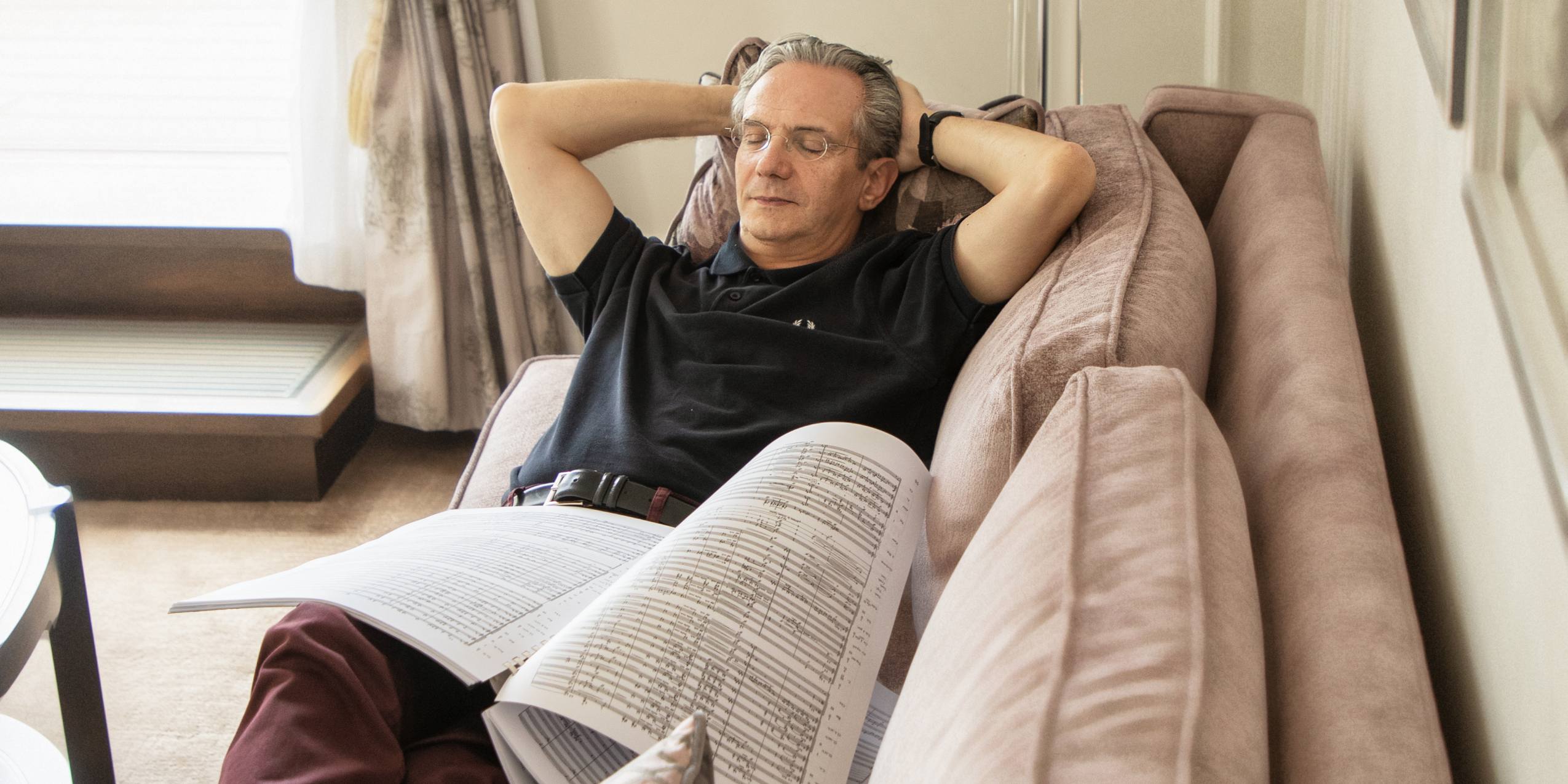 Dirigent Fabio Luisi ligger i en sofa og læser noder