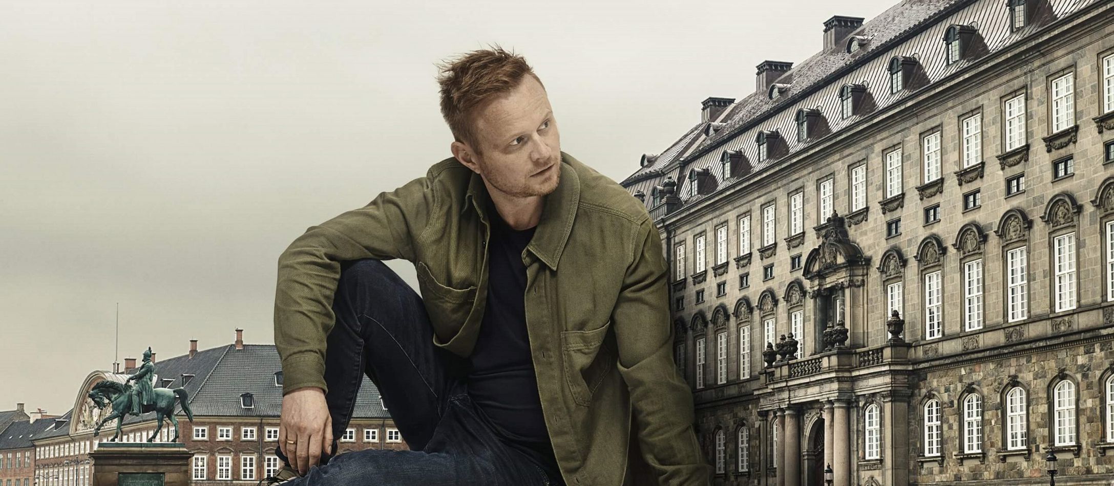 Siddende Jonathan Spang kigger mød sin venstre side foran Amalienborg