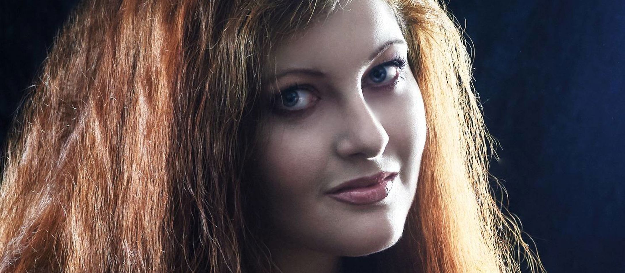 Maria Schellenberg med rødbrunt kruset hår kigger mod kameraet