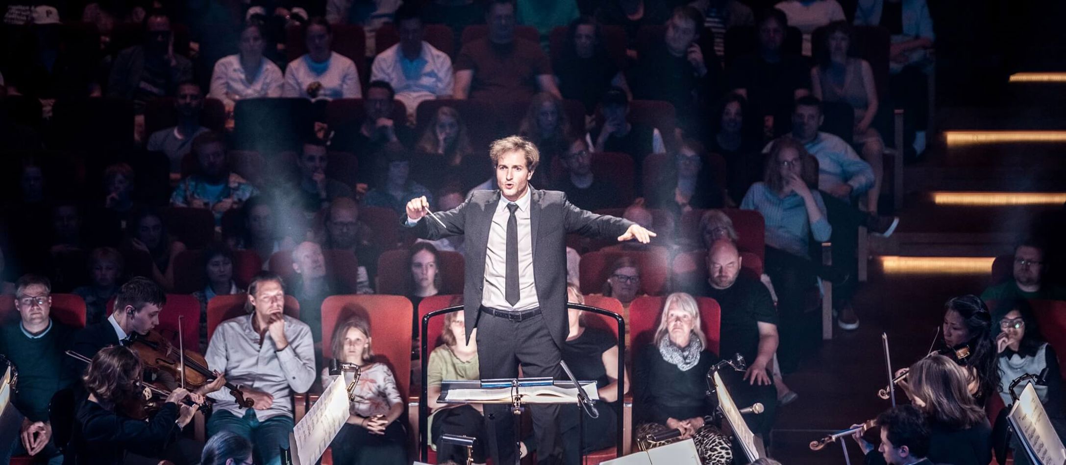 Koncentreret Christian Schumann i færd med at dirigere et stort orkester i et dramatisk lyssetting