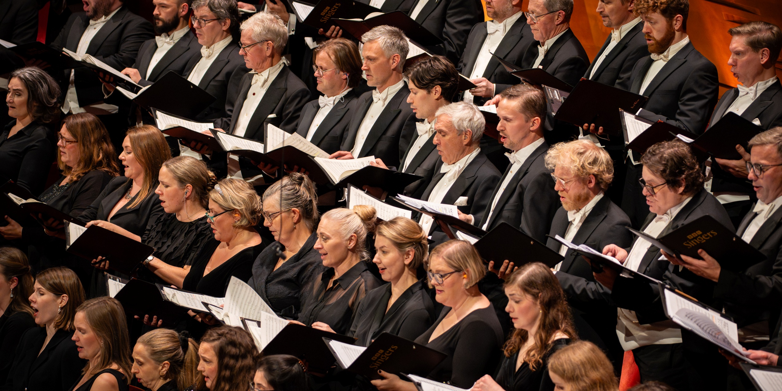 Korsangere med noder, der synger i Koncertsalen