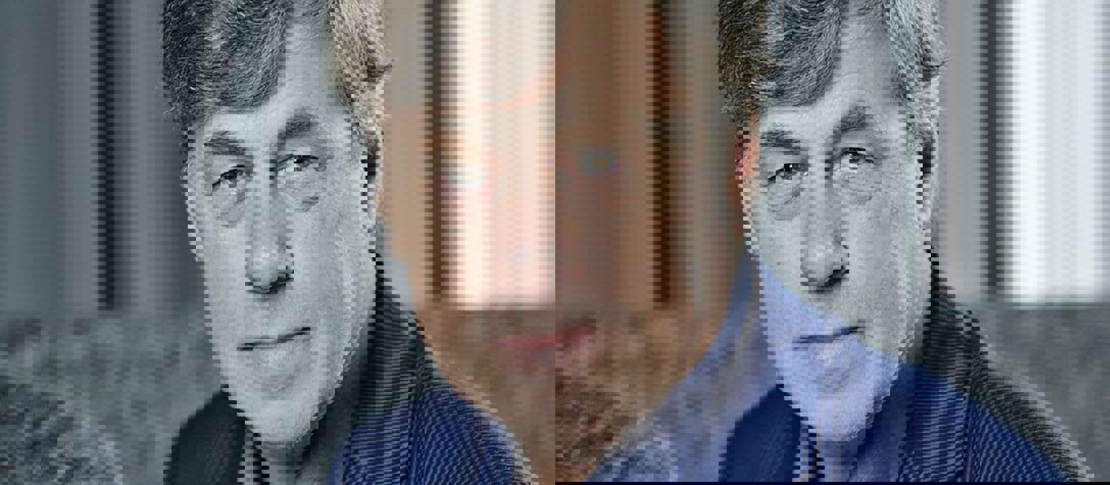 Siddende Paul Hillier med gråt hår kigger afslappet iført lyseblå skjorte og mørkeblå jakke.