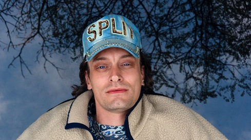 Casper Clausen med kasket og blålig baggrund