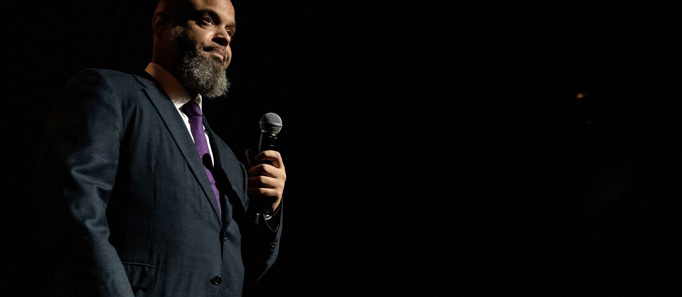 Æresgæsten Paul Ellington med langt skæg, lilla slips og sort jakke med mikrofon i hånden