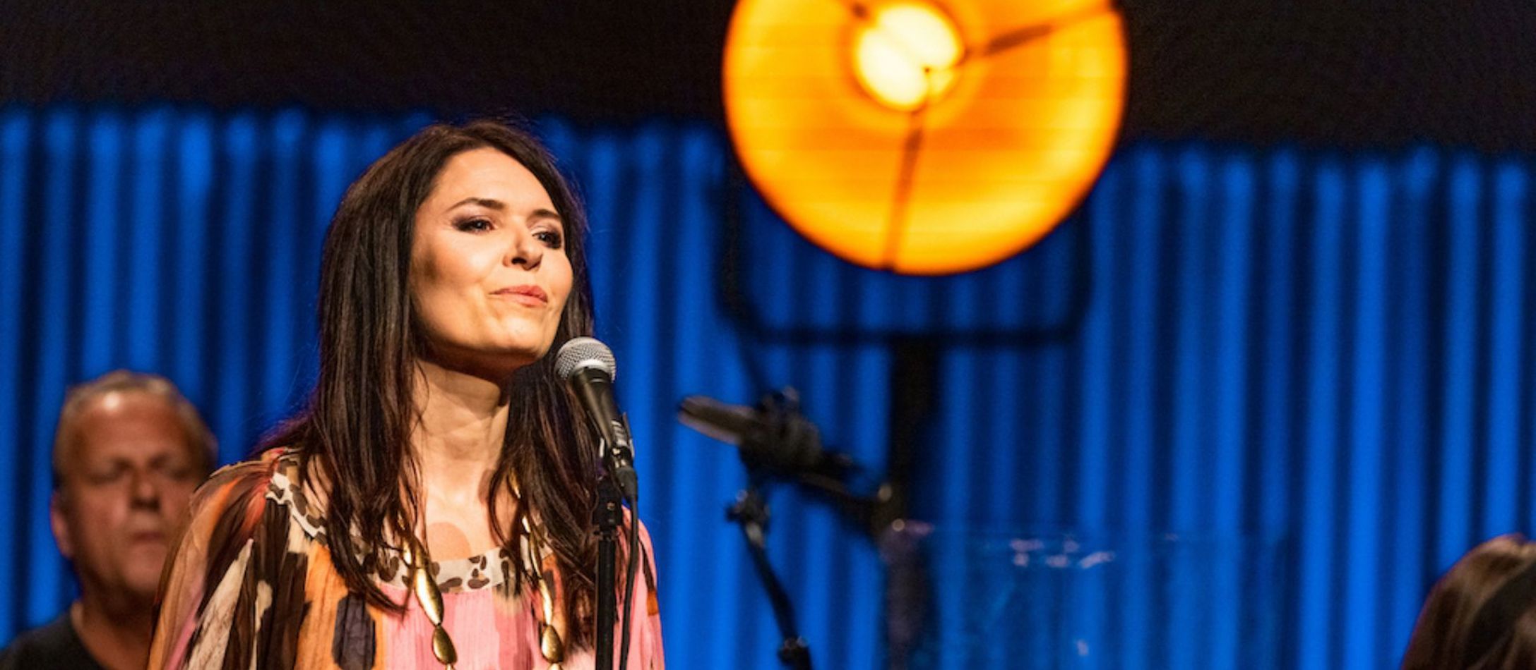 Kira Skov synger foran blå baggrund til koncert.
