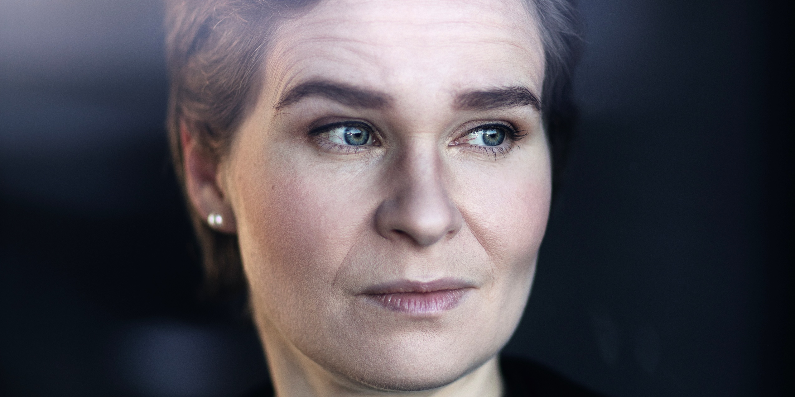 Kvinde der kigger til siden med mørk baggrund