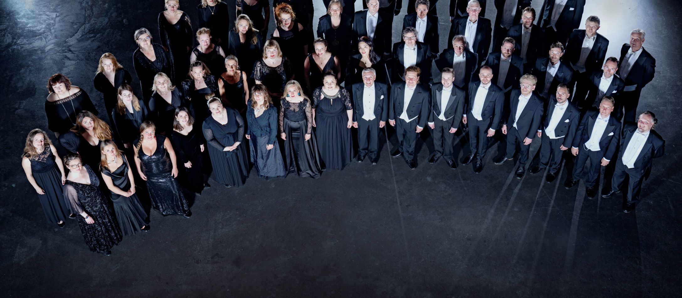 DR Koncertkoret iført formelt tøj foran sort baggrund