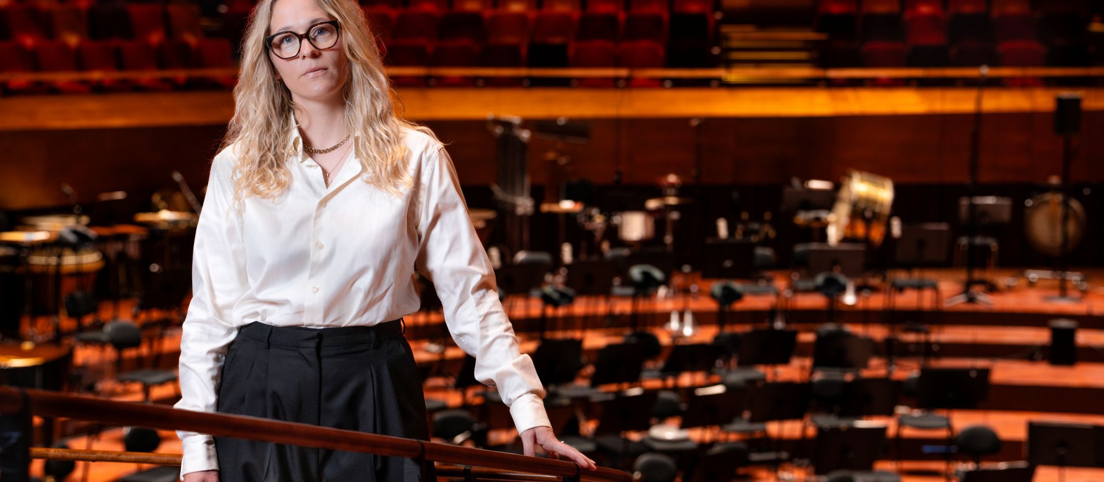 Kvinde i hvid skjorte foran scenen i koncertsalen