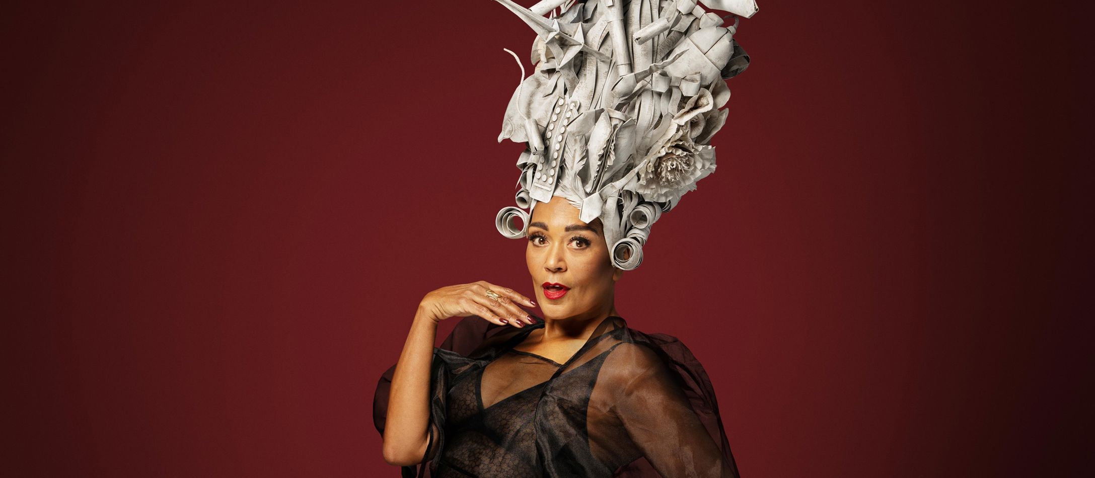 Caroline Henderson foran mørkerød baggrund med sølvfarvet hovedbeklædning ifbm. hendes koncert i DR Koncerthuset.