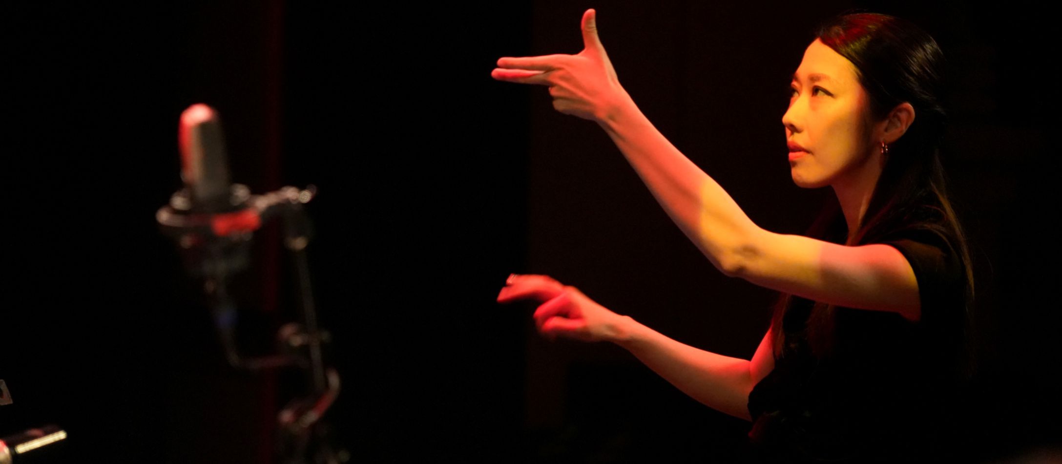 Kvinde med løftede arme der dirigere.