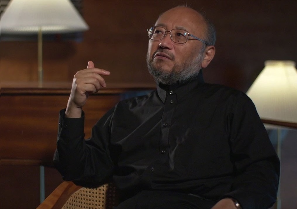 Chefakustiker Yasuhita Toyota iført sortknappet skjorte sidder i kongesuiten i DR Koncerthuset med den ene hånd hævet blidt.