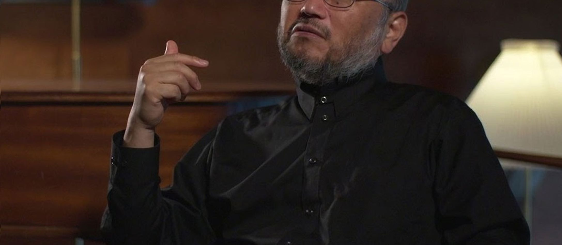 Chefakustiker Yasuhita Toyota iført sortknappet skjorte sidder i kongesuiten i DR Koncerthuset med den ene hånd hævet blidt.